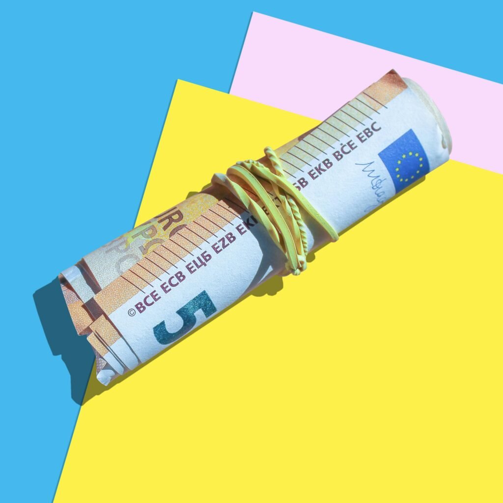 High angle shot of rolled euro notes with rubber band on vibrant surfaces.